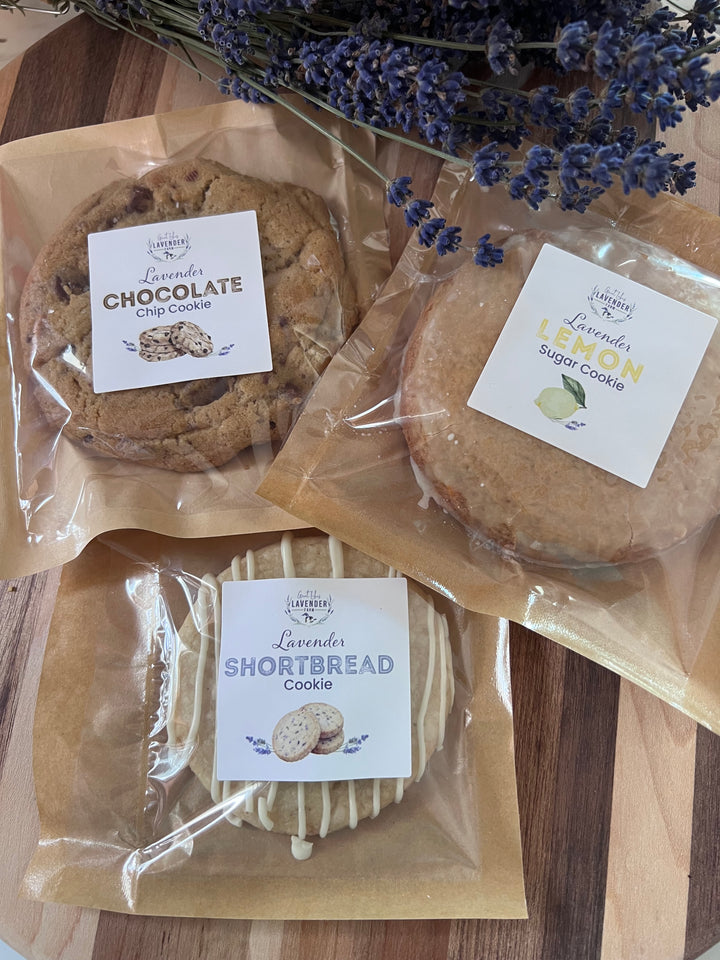 Lavender Cookies in clear bags labeled Chocolate Chip, Lemon Sugar and Shortbread on a wooden board
