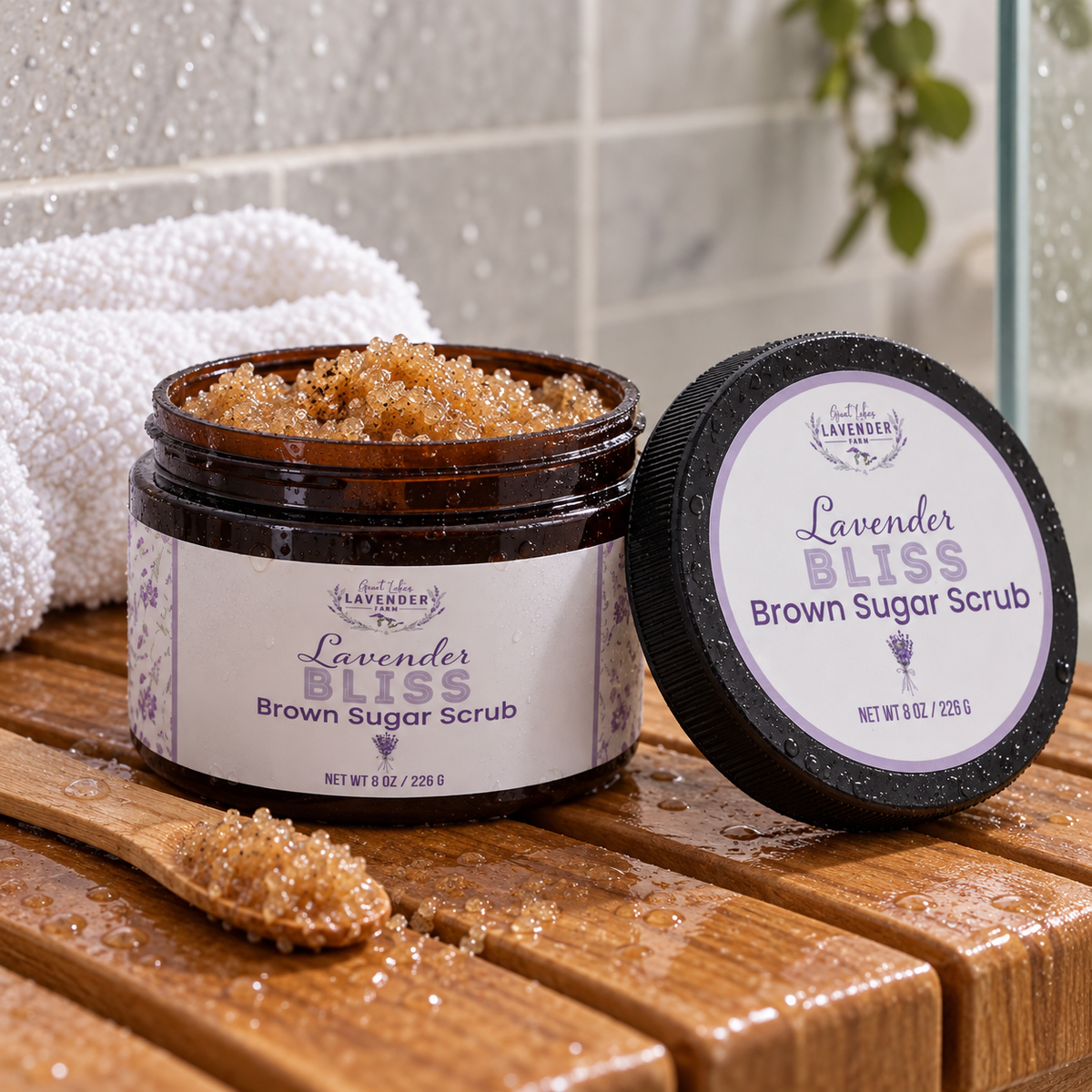 Lavender Bliss Brown Sugar Scrub in an open amber jar with a spoon of scrub on a wet wooden shower bench