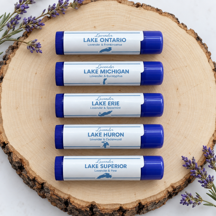 Five lavender lip balms labeled by Great Lakes: Ontario, Michigan, Erie, Huron, Superior on wood.