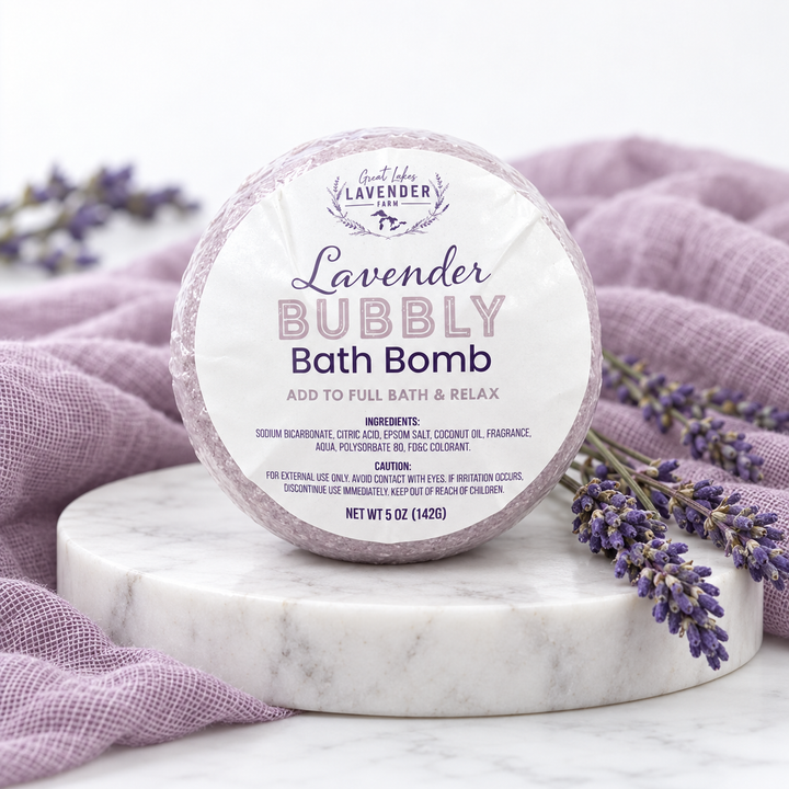 Lavender Bubbly Bath Bomb 5 oz in label wrap on a marble round with purple cloth and lavender