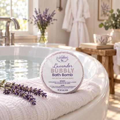 Lavender Bubbly Bath Bomb in label wrap on a towel at the edge of a filled bathtub