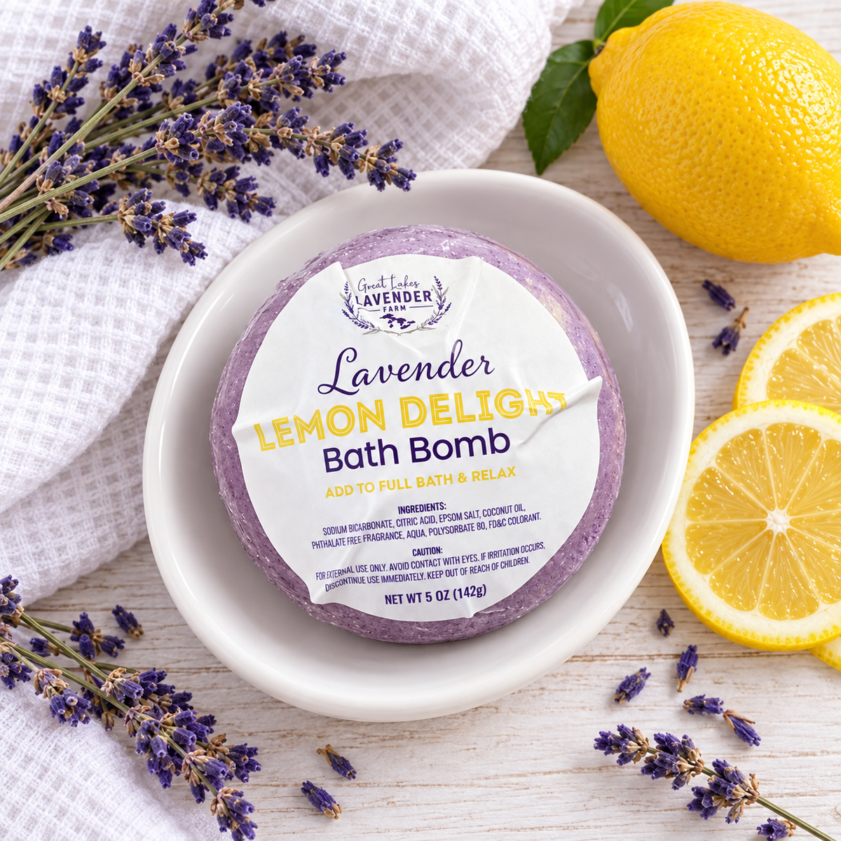 Lavender Lemon Delight Bath Bomb in label wrap on a white dish with lemon slices and lavender