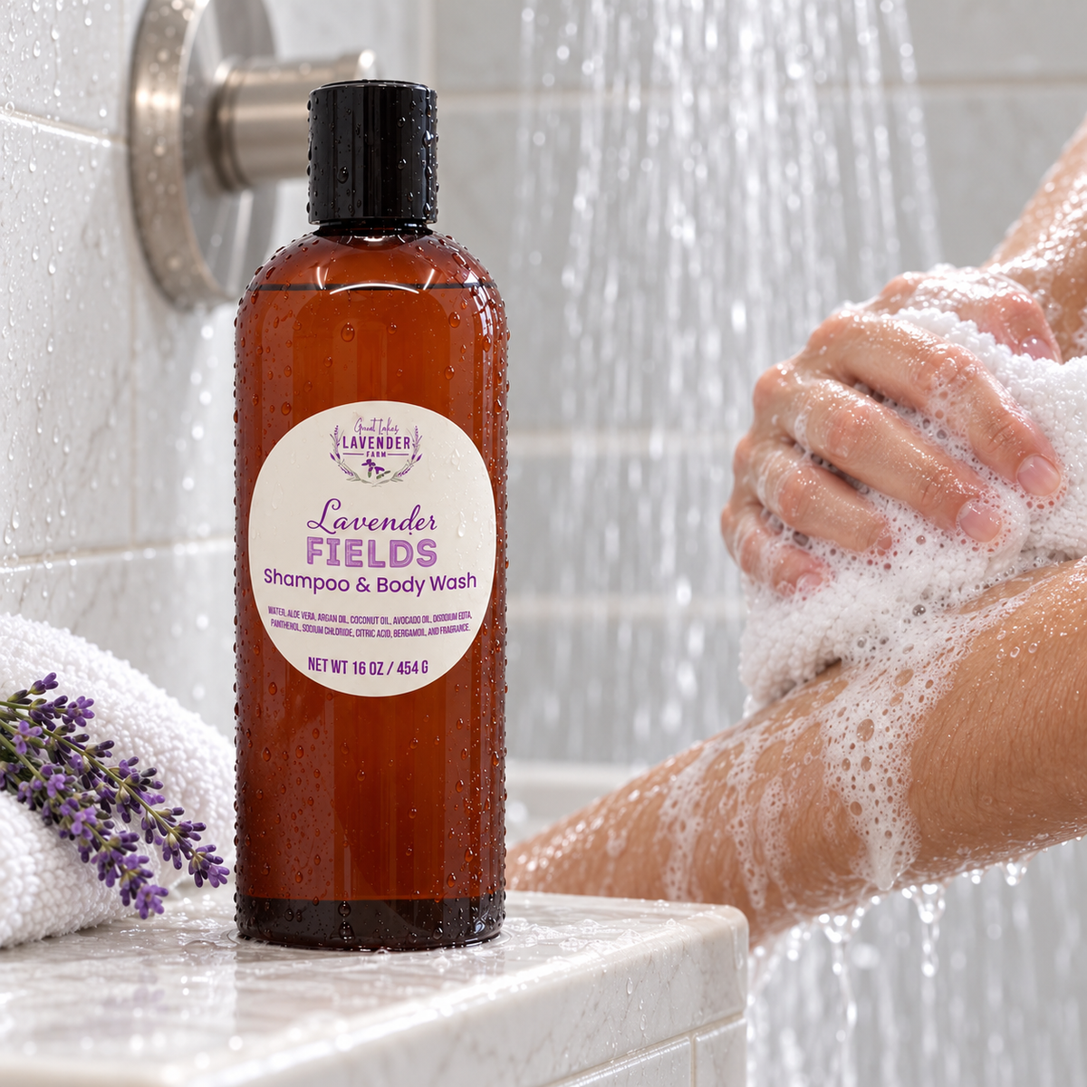 Lavender Fields Shampoo & Body Wash on a shower ledge as a person lathers their arm under running water