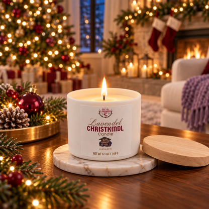 Lavender Christkindl Candle, small, lit on a marble coaster with a Christmas tree and fireplace behind