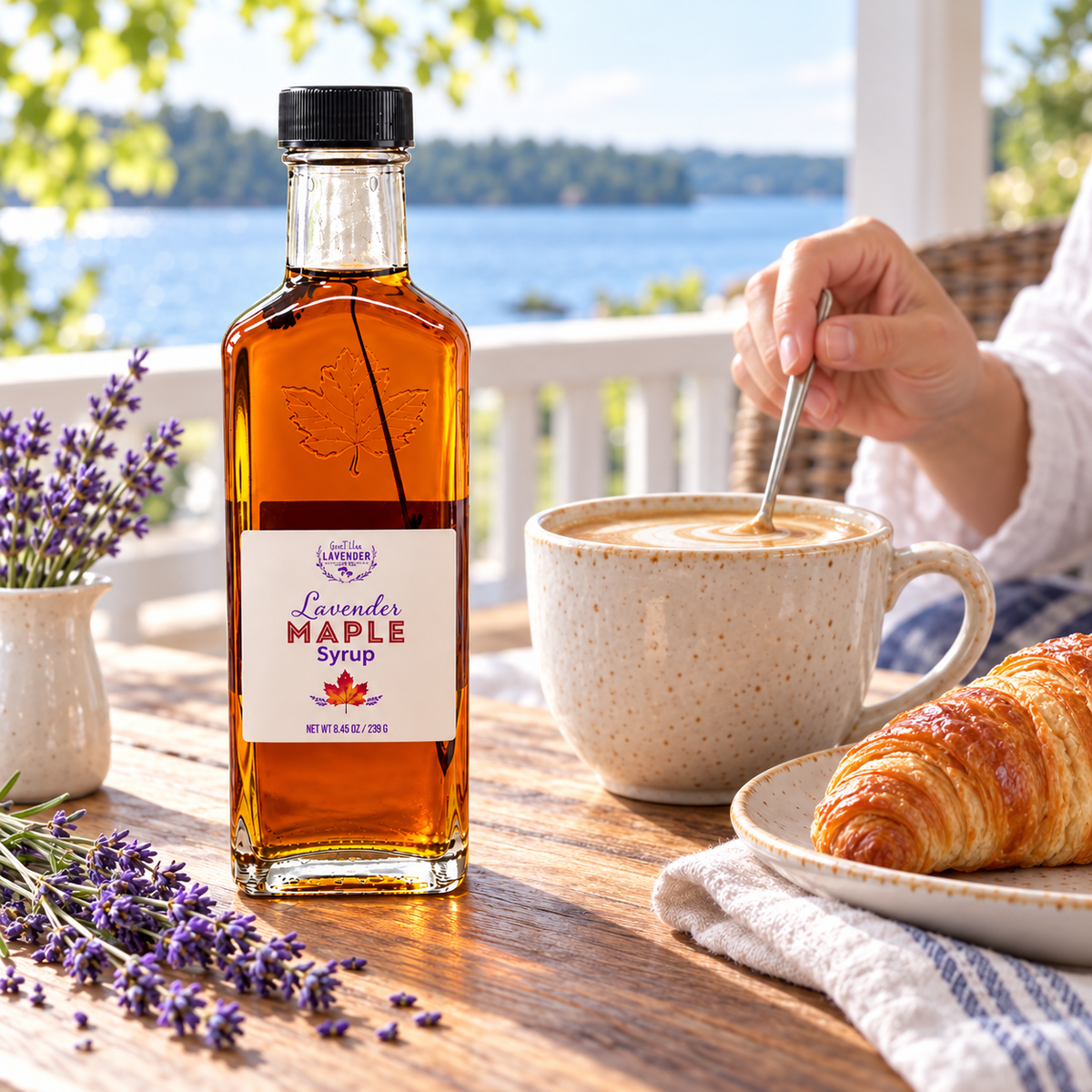 Lavender Maple Syrup bottle on a porch table by the lake with a latte and a croissant