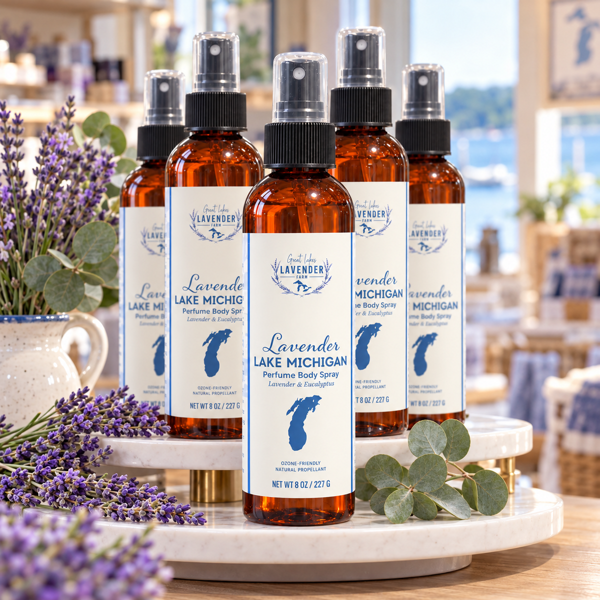 Several Lavender Lake Michigan Perfume Body Sprays on a marble riser with lavender and eucalyptus