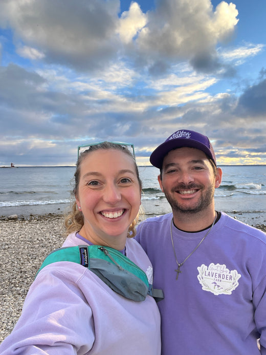 Sierra and Andrew in farm sweatshirts on a pebble beach