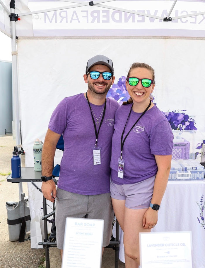 Sierra and Andrew in purple shirts at their market booth