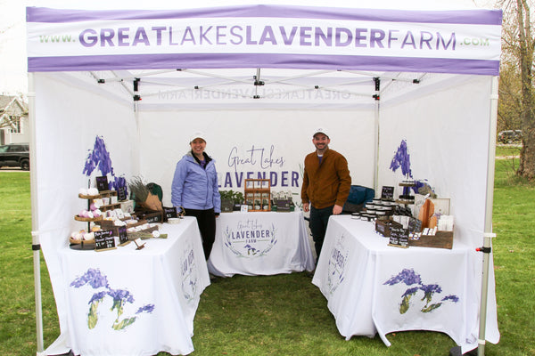 Sierra and Andrew standing in their Great Lakes Lavender Farm market tent full of products