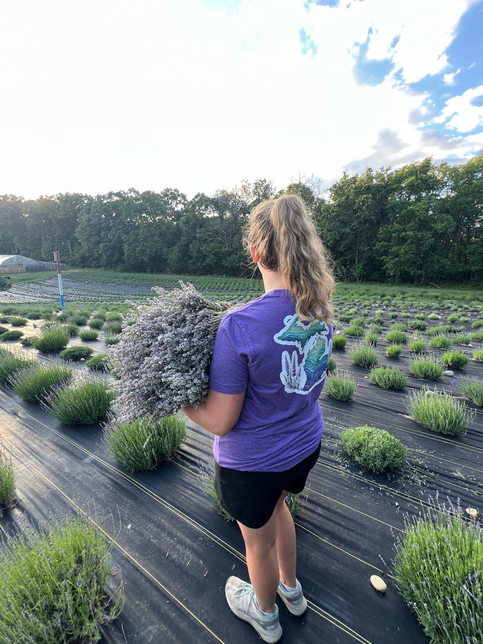 Woman seen from behind carrying lavender in a Michigan shirt