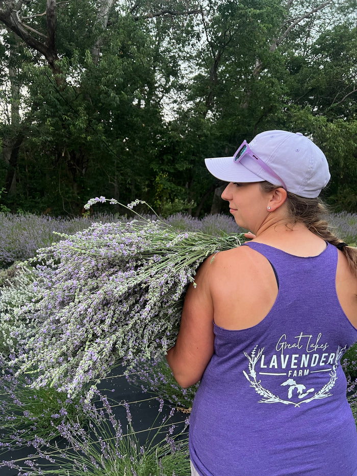 Woman in a farm tank top carrying a large lavender bundle