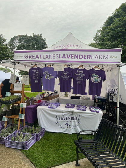Market tent with purple farm and faith t-shirts on hangers