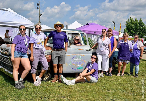 Group of lavender growers in purple shirts posing around a vintage truck at the Michigan Lavender Festival