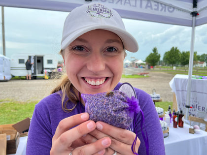 Smiling woman holding a purple lavender sachet with a bee on it