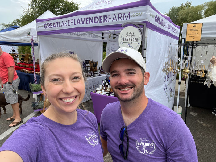Selfie of Sierra and Andrew in farm shirts in front of their market tent